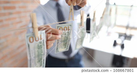 Man hanging american dollar bills on rope closeup Man hanging american dollar bills on rope closeup 108667801