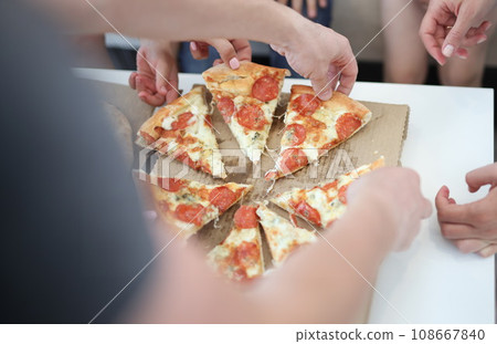 Group of people taking slices of pizza closeup Group of people taking slices of pizza closeup 108667840