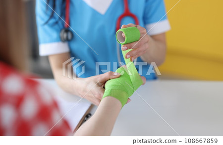 Doctor traumatologist bandages hand of child closeup 108667859