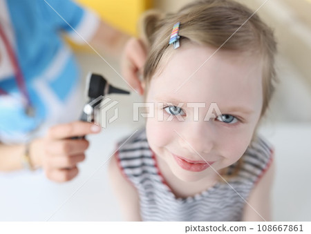 Doctor examining ear with otoscope for little smiling girl 108667861