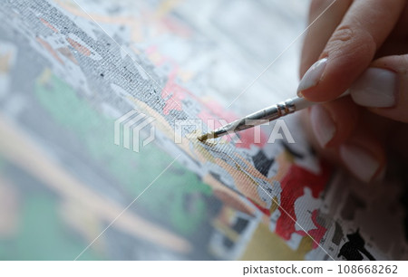 Woman paints picture with watercolors and holds brush Woman paints picture with watercolors and holds brush 108668262