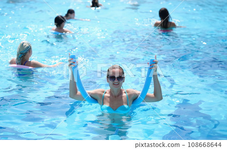 Happy smiling fitness woman exercising in noodle pool 108668644