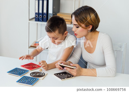 a boy with a psychologist in the office plays board games a boy with a psychologist in the office plays board games 108669756