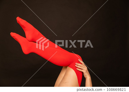 women's slender legs in red stockings on a black background women's slender legs in red stockings on a black background 108669821