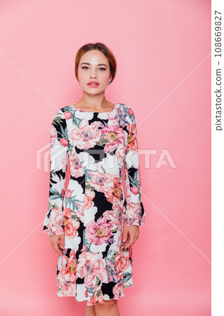 a beautiful woman in a floral dress poses on a pink background a beautiful woman in a floral dress poses on a pink background 108669827