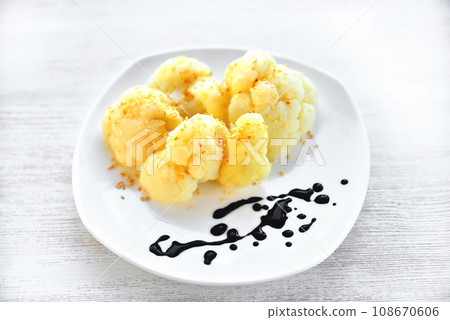Cauliflower on a white plate drops of sauce, light natural wooden background Cauliflower on a white plate drops of sauce, light natural wooden background 108670606