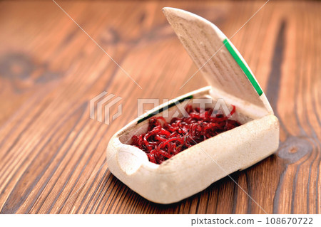 winterworm for winter fishing in a box on a brown wooden background winterworm for winter fishing in a box on a brown wooden background 108670722