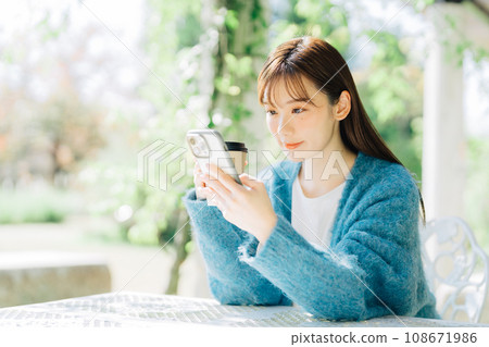 Woman looking at smartphone on terrace 108671986