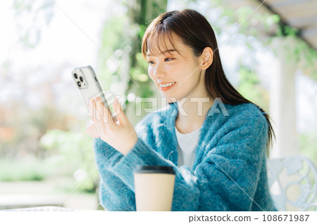 Woman looking at smartphone on terrace 108671987