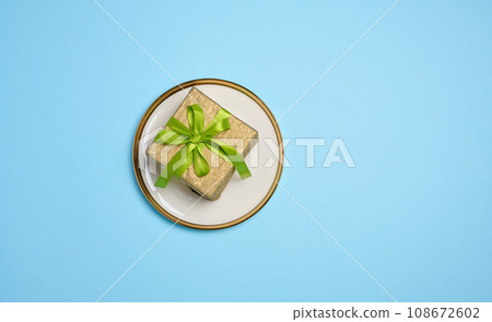 Gift box lies in a round plate on a blue background, top view 108672602