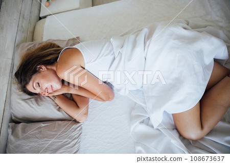a woman sleeps in a bed in a bedroom room in the morning rest 108673637