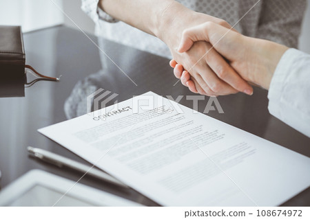 Business people signing contract papers while sitting at the glass table in office, closeup. Partners or lawyers working together at meeting. Teamwork, partnership, success concept 108674972