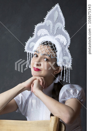 Portrait of a beautiful girl in a snow maiden costume. Russian snow girl in a crown. 108675343
