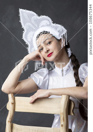 Portrait of a beautiful girl in a snow maiden costume. Russian snow girl in a crown. 108675344