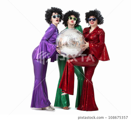A group of girls with a disco ball in colorful costumes in the fashion style of the seventies or eighties. Disco party on a white background. A group of girls with a disco ball in colorful costumes in the fashion style of the seventies or eighties. Disco party on a white background. 108675357