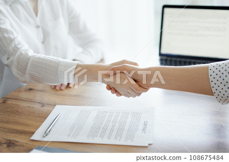 Business people shaking hands above contract papers just signed on the wooden table, close up. Lawyers at meeting. Teamwork, partnership, success concept 108675484