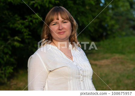 A plump blonde with blue eyes looks into the camera. A plump blonde with blue eyes looks into the camera. 108675957