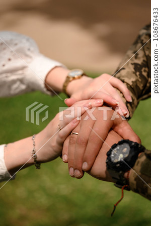 Hands of the bride and groom with rings on their fingers close-up. Groom in military uniform. 108676433