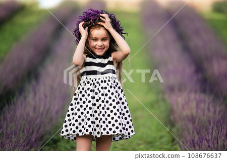 a cute little girl is smiling and fixing her crown that flew off her head 108676637