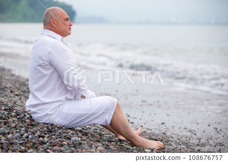 Elderly handsome athletic man looks at the sea waves. Elderly handsome athletic man looks at the sea waves. 108676757
