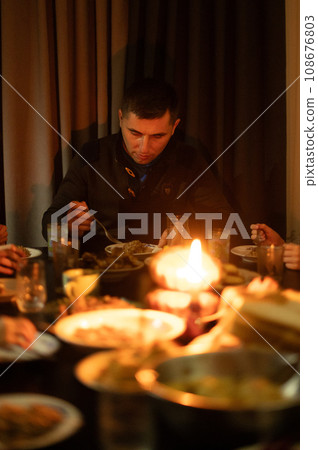 Christmas Eve in a Ukrainian family. Kutya on the table and a lighted candle. The man is having dinner on Christmas Eve. Christmas Eve in a Ukrainian family. Kutya on the table and a lighted candle. The man is having dinner on Christmas Eve. 108676803
