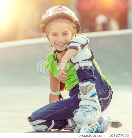 Cute little girl on roller skates in helmet at a park Cute little girl on roller skates in helmet at a park 108677693
