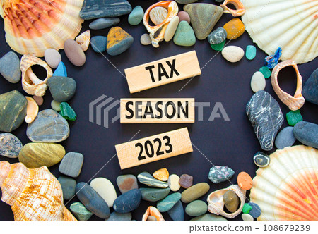 Tax season 2023 symbol. Concept words Tax season 2023 on wooden blocks on a beautiful black table black background. Sea stone, sea shell. Business Tax season 2023 concept. Copy space. 108679239