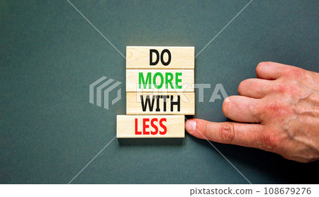 Do more with less symbol. Concept word Do more with less on beautiful wooden block. Beautiful grey table grey background. Businessman hand. Business do more with less concept. Copy space. Do more with less symbol. Concept word Do more with less on beautiful wooden block. Beautiful grey table grey background. Businessman hand. Business do more with less concept. Copy space. 108679276