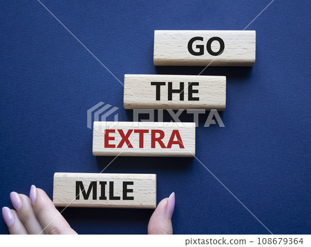Go the extra mile symbol. Wooden blocks with words Go the extra mile. Businessman hand. Beautiful deep blue background. Business and Go the extra mile concept. Copy space. Go the extra mile symbol. Wooden blocks with words Go the extra mile. Businessman hand. Beautiful deep blue background. Business and Go the extra mile concept. Copy space. 108679364