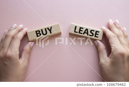 Buy or Lease symbol. Concept word Buy or Lease on wooden blocks. Businessman hand. Beautiful pink background. Business and Buy or Lease concept. Copy space Buy or Lease symbol. Concept word Buy or Lease on wooden blocks. Businessman hand. Beautiful pink background. Business and Buy or Lease concept. Copy space 108679462