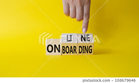Online Onboarding symbol. Businessman Hand points at turned wooden cubes with words Online Onboarding. Beautiful yellow background. Business and Online Onboarding concept. Copy space 108679646