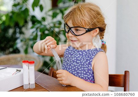 Little preschool girl doing chemical experiment in laboratory at school. Toddler child with protective glasses study dropping liquid to test tube , caucasian , biochemistry . chemistry class. Little preschool girl doing chemical experiment in laboratory at school. Toddler child with protective glasses study dropping liquid to test tube , caucasian , biochemistry . chemistry class. 108680760