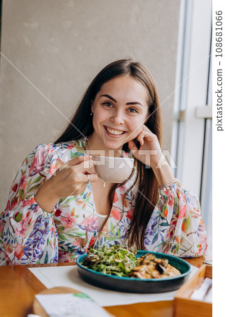 Young beautiful stylish woman drinking coffee while sitting in restaurant and eating tasty dish Young beautiful stylish woman drinking coffee while sitting in restaurant and eating tasty dish 108681066