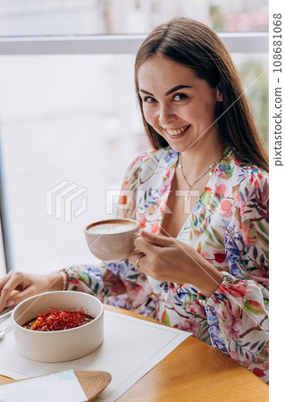 Young beautiful stylish woman drinking coffee while sitting in restaurant and eating tasty dish 108681068