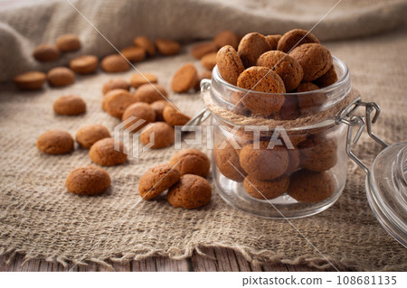 Pepernoten cookies in glass jar on sackcloth. Traditional sweets for St. Nicholas Day 108681135