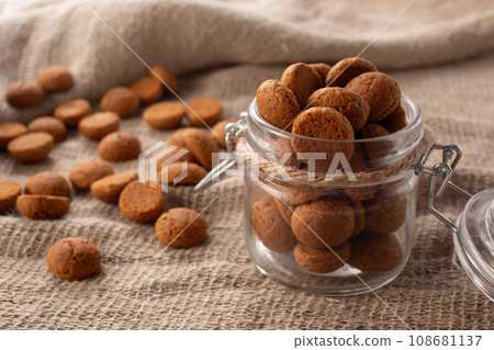 Pepernoten cookies in glass jar on sackcloth. Traditional sweets for St. Nicholas Day 108681137