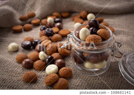 Pepernoten cookies in glass jar on sackcloth. Traditional sweets for St. Nicholas Day 108681141