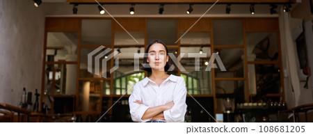 Smiling young female manager, cafe owner cross arms on chest, looking confident, standing in front of restaurant Smiling young female manager, cafe owner cross arms on chest, looking confident, standing in front of restaurant 108681205