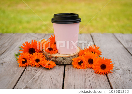 Calendula flowers are lying on an old wooden table near a glass of coffee or tea. Phytotherapy. Calendula flowers are lying on an old wooden table near a glass of coffee or tea. Phytotherapy. 108681233