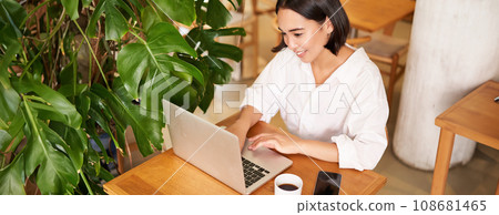 Working woman in cafe, using laptop, studying remotely, freelancing from restaurant, drinking coffee Working woman in cafe, using laptop, studying remotely, freelancing from restaurant, drinking coffee 108681465