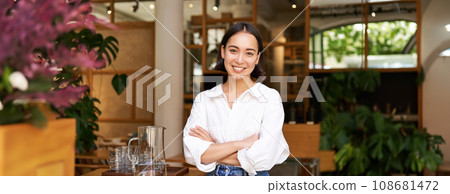 Young asian woman, cafe owner or manager, standing confident with arms crossed on hands, smiling and looking at camera Young asian woman, cafe owner or manager, standing confident with arms crossed on hands, smiling and looking at camera 108681472