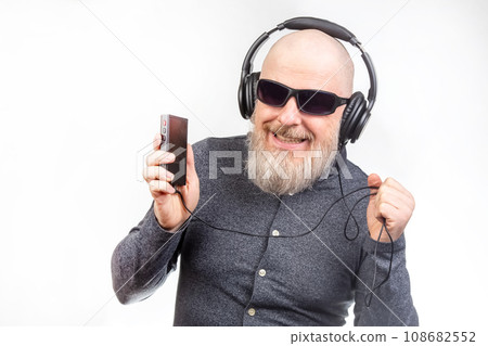bearded man in sunglasses and headphones listens to music. audio sound style and technology 108682552