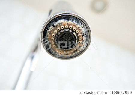 The chrome faucet is covered with lime scale. 108682939