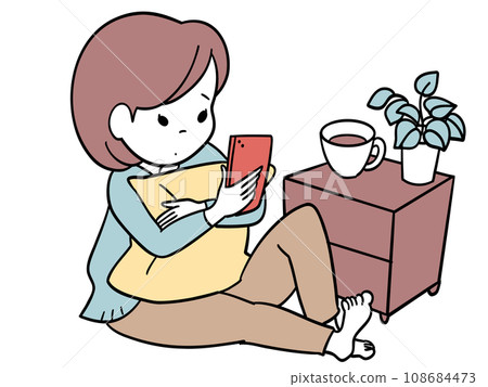 A girl holding a cushion and looking at her smartphone leisurely 108684473