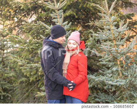 Happy woman and man hugging at Christmas Market in front of Christmas tree. Happy woman and man hugging at Christmas Market in front of Christmas tree. 108685607