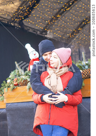 Happy girl and boy hugging in front of Christmas decoration in winter. Happy girl and boy hugging in front of Christmas decoration in winter. 108685613