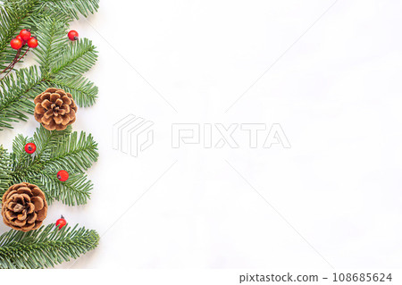 Green branches with red berries and brown cones to the left on white background. Green branches with red berries and brown cones to the left on white background. 108685624