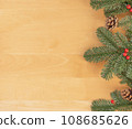 Christmas flat lay of green fir branches, red berries and brown cones at the right. 108685626