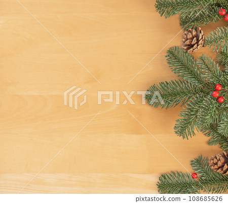 Christmas flat lay of green fir branches, red berries and brown cones at the right. Christmas flat lay of green fir branches, red berries and brown cones at the right. 108685626