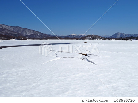 Frozen Lake Hibara in Fukushima Prefecture. In March, cracks appear in the white snowy field, and they look impressive and beautiful against the clear blue sky. 108686720